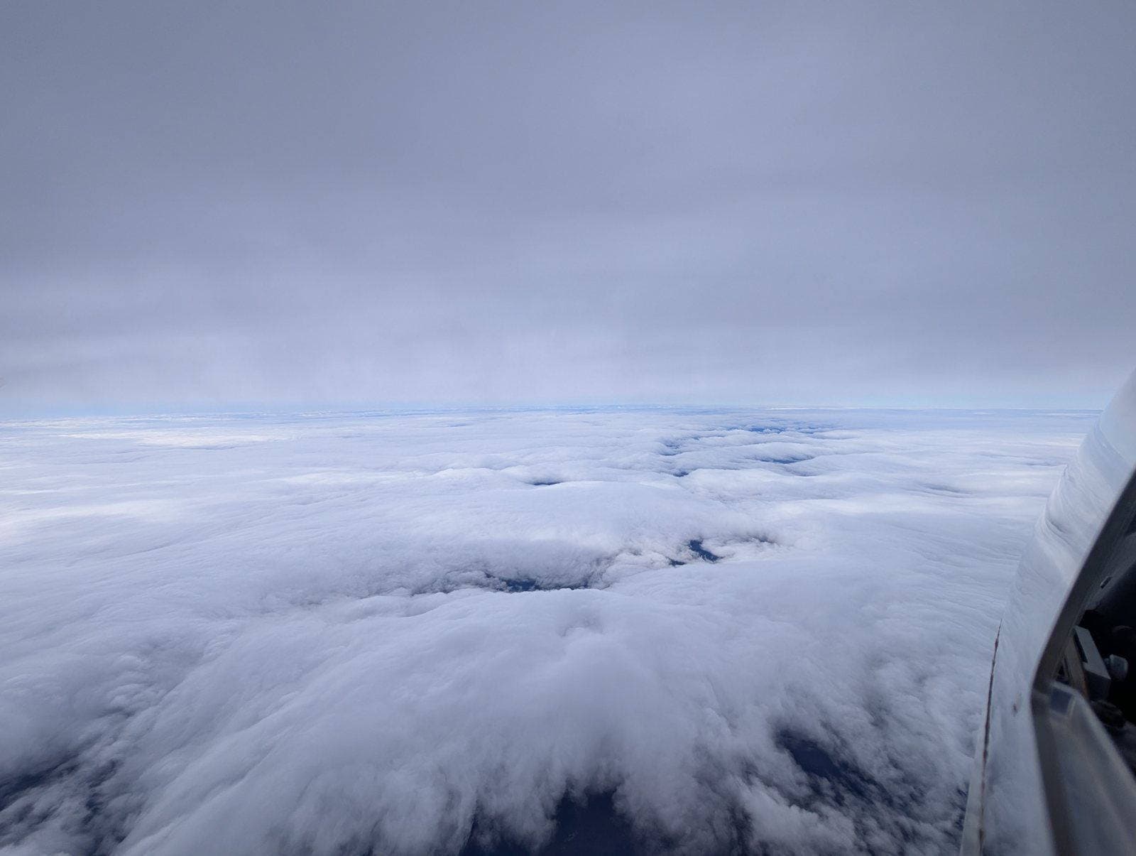 A sea of undercast stretching to the horizon, seen from the wing of a glider