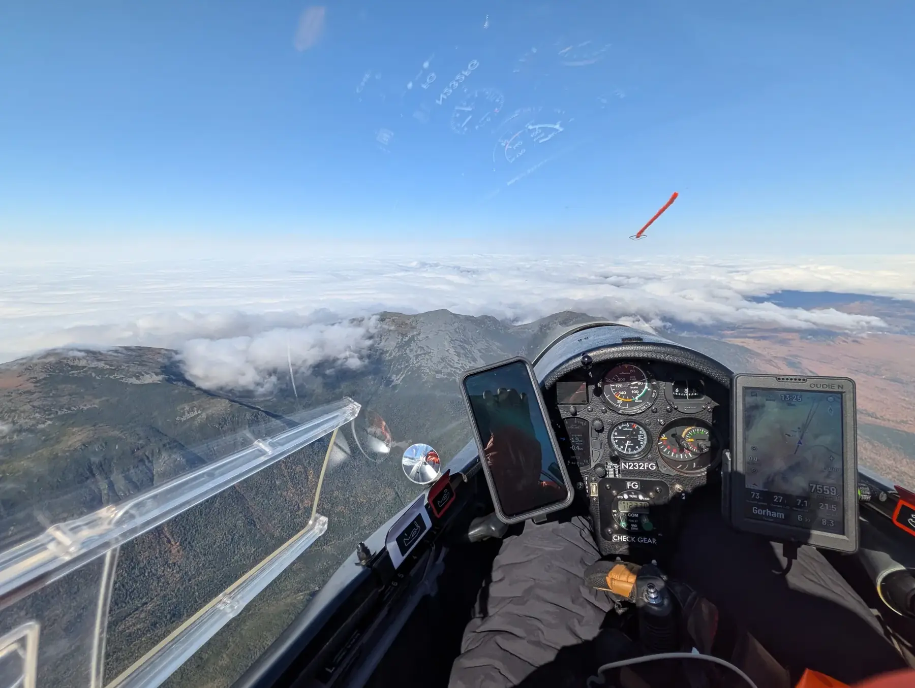 Cockpit view of a glider over the mountains, with the flight computer showing 7,559 feet at 13:25