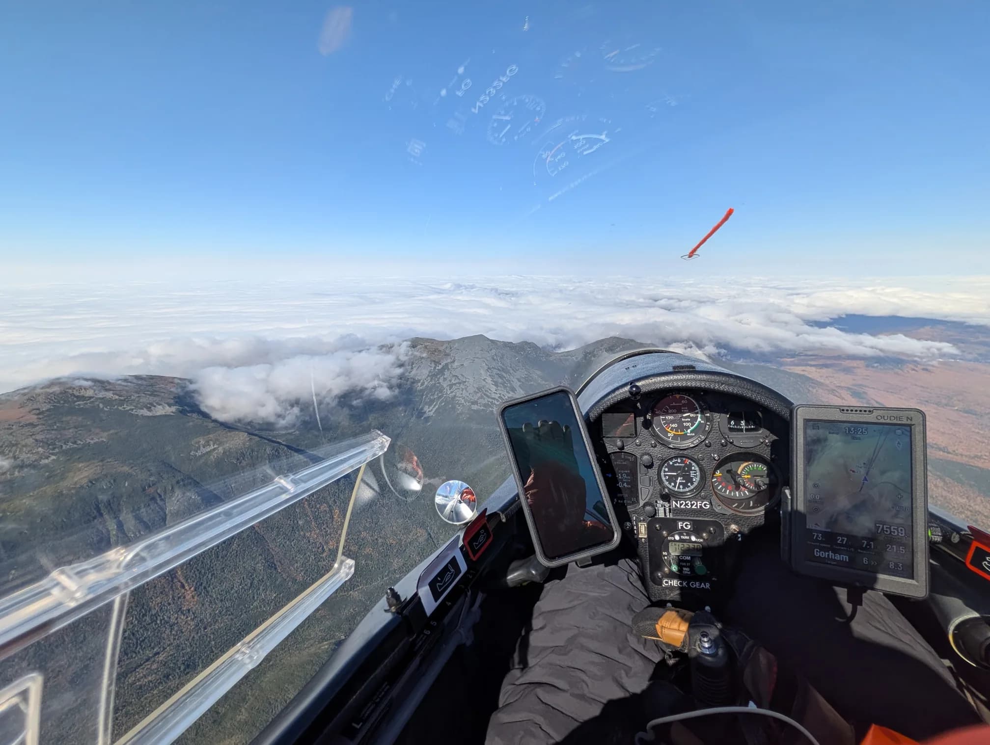 Cockpit view of a glider over the mountains, with the flight computer showing 7,559 feet at 13:25