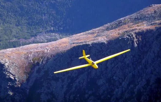 A yellow glider flying along a ridge in the White Mountains
