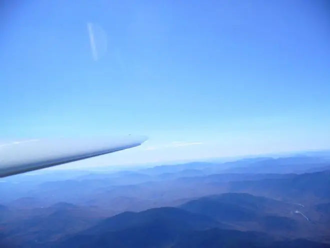 A glider wingtip over ridges stretching into the distance